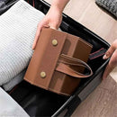 Brown leather wallet being placed into a suitcase