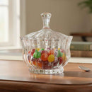 Clear glass candy dish filled with colorful candies on a wooden surface.