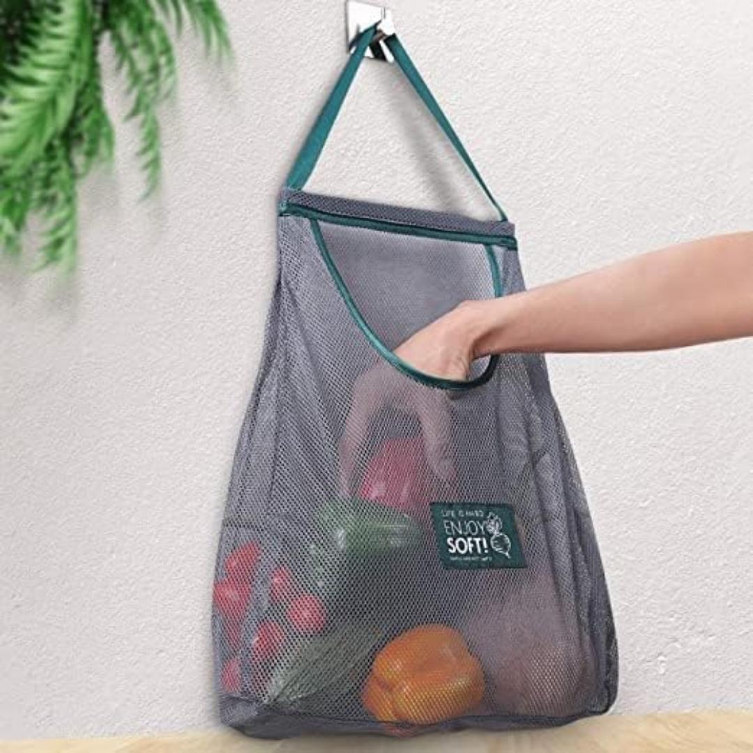 Person holding a mesh grocery bag with produce against a light background