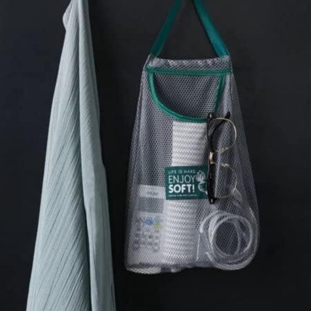 Mesh laundry bag with cleaning supplies hanging on a hook against a black background