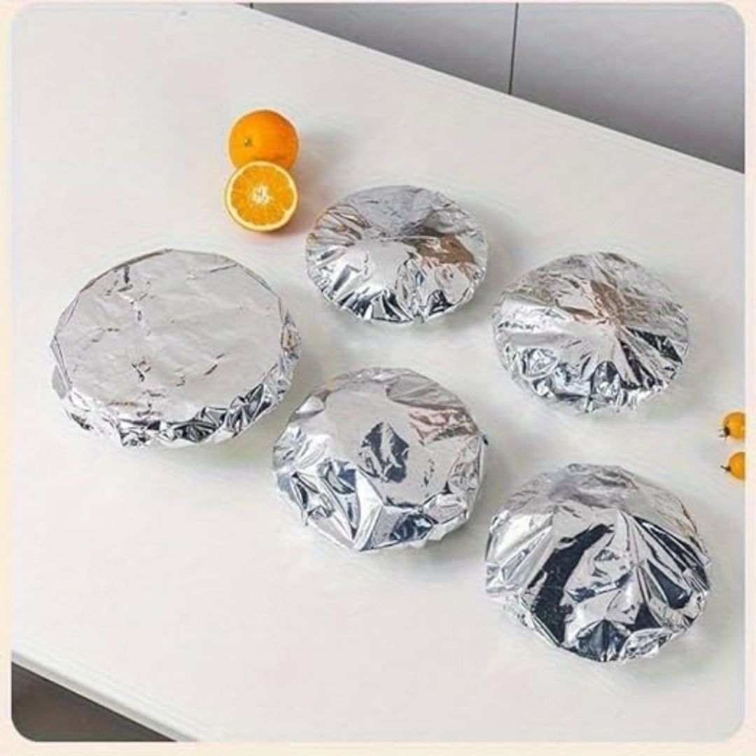 Silver foil-wrapped items on a white surface with oranges in the background