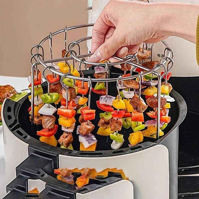 Hand placing skewers with vegetables and meat into an air fryer basket.