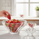 Clear glass bowl filled with strawberries on a wooden table.