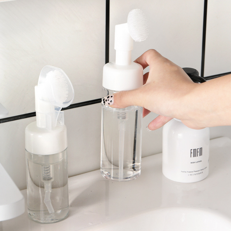 Foaming Soap Dispenser With Silicone Brush Placed on Bathroom Counter – Hand Reaching for Bottle – Cupindy