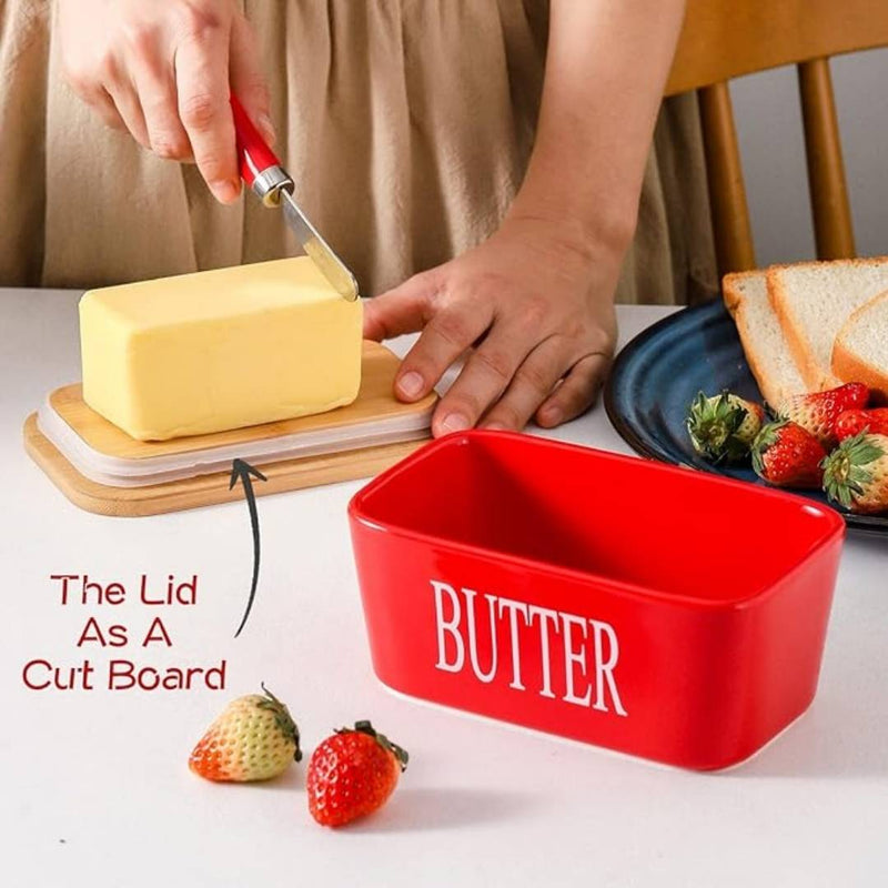 Red butter container with lid as a cutting board, butter being spread on bread.