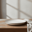 White ceramic bowl with black rim on a wooden surface with a neutral background