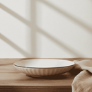 White ceramic bowl on a wooden surface with a beige towel and light background