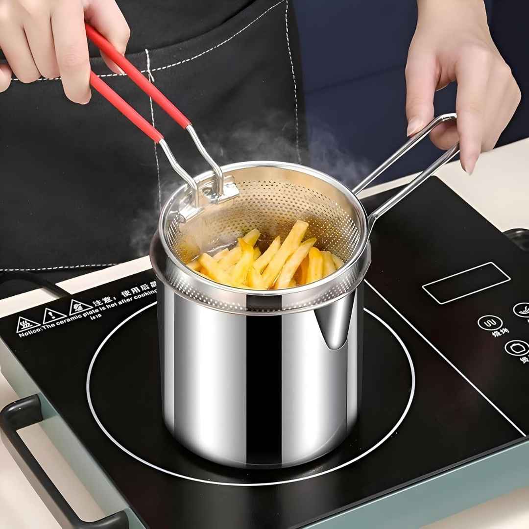 Stainless steel pot with strainer on a induction cooktop, filled with hot oil and frying chips.
