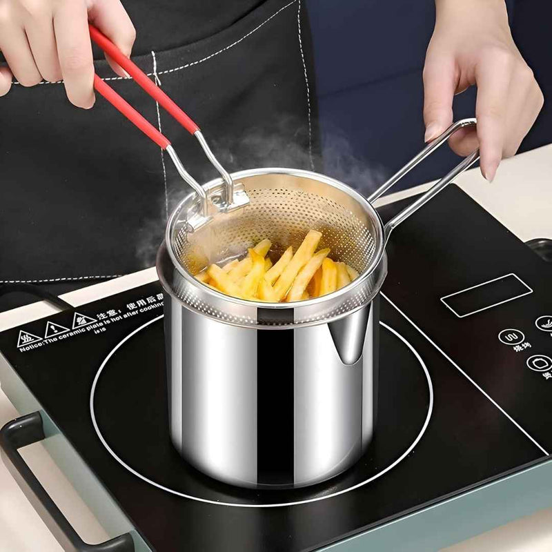 Stainless steel pot with strainer on a induction cooktop, filled with hot oil and frying chips.
