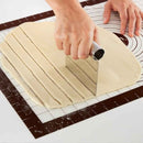 Person using a dough roller to cut dough into strips on a cutting mat.