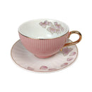 Pink teacup and saucer with floral design on a white background