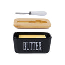 Black butter dish with wooden lid and white knife on a white background