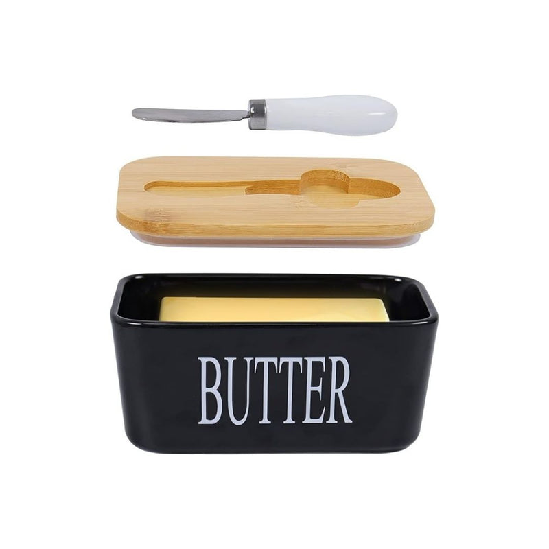 Black butter dish with wooden lid and white knife on a white background