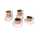 Set of miniature pink cups with gold trim on white saucers against a white background