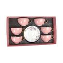 Set of pink ceramic cups with a decorative white saucer in a box on a white background