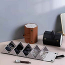 Eyewear display case with glasses and a watch, accompanied by a brown leather case and a black one on a light surface.