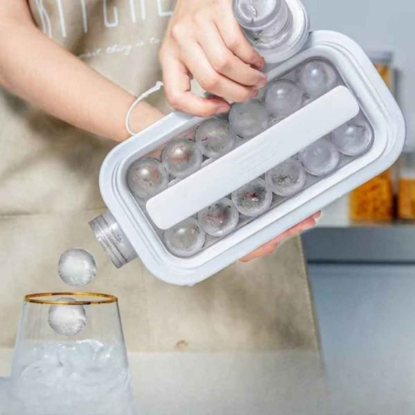 Person using a white ice cube tray to pour frozen cubes into a glass.