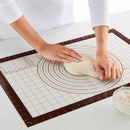 Person kneading dough on a baking mat with measurements