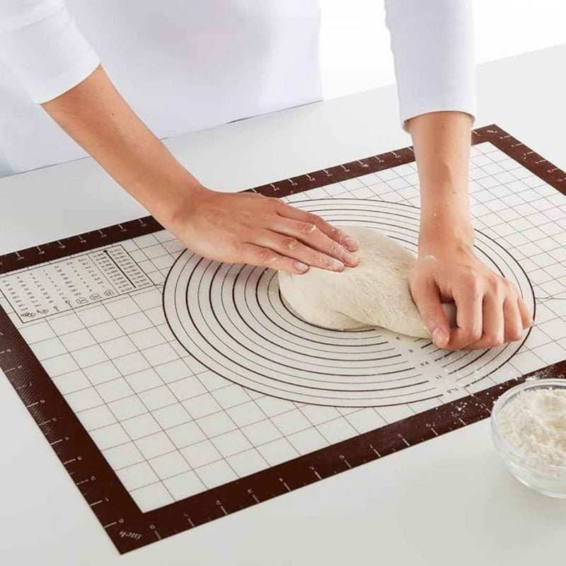Person kneading dough on a baking mat with measurements