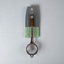Metallic strainer with wooden handle on a gray background