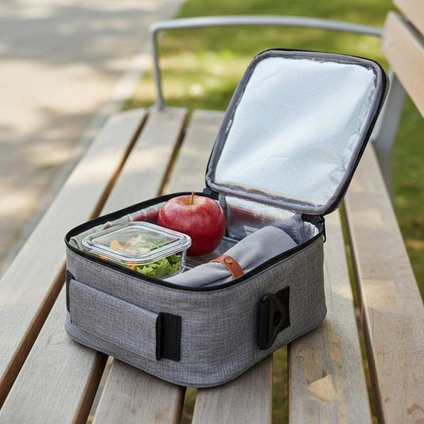 Lunch bag with food items on a wooden table outdoors