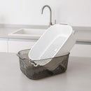 White colander inside a gray basket on a kitchen counter with a sink in the background.