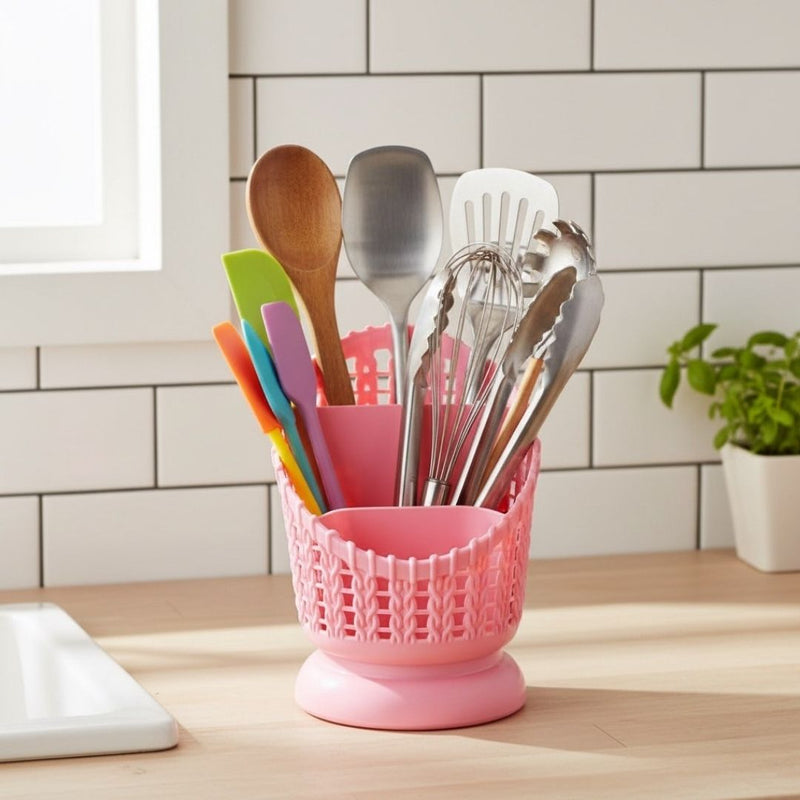 Pink utensil holder with kitchen tools on a wooden countertop.