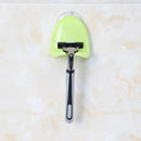 Green suction cup holder for razors in a bathroom setting.